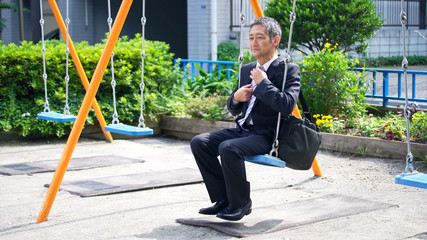 ブランコに乗る中高年男性