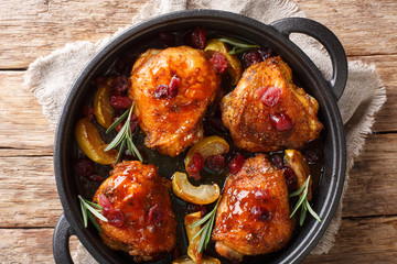 Holiday food hot baked chicken thighs with apples, cranberries and rosemary closeup in a pan. Horizontal top view