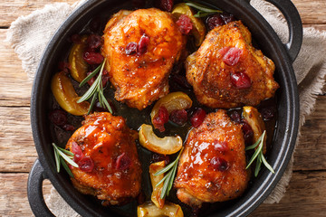 Rustic style baked chicken thighs with apples, cranberries and rosemary close-up in a pan. Horizontal top view