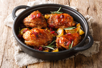 Holiday food hot baked chicken thighs with apples, cranberries and rosemary closeup in a pan....