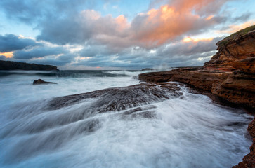 Waves crash onto the rocky shore of Bare Island