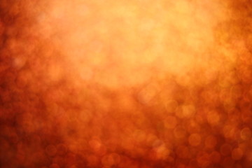 Blurred sparkle glowing dark orange glitter bokeh of carborundum abstract textured background, can use for celebrate christmas day, new year day, halloween day or birthday