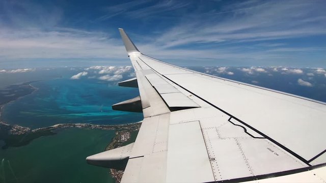 Airplane window shows off wing and cancun beaches