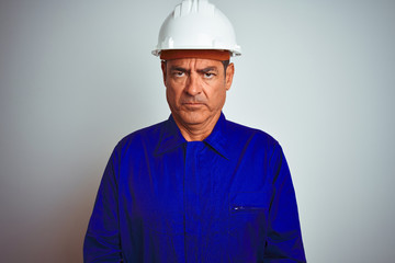 Handsome middle age worker man wearing uniform and helmet over isolated white background skeptic and nervous, frowning upset because of problem. Negative person.