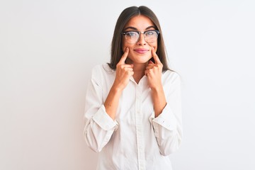 Young beautiful businesswoman wearing glasses standing over isolated white background Smiling with open mouth, fingers pointing and forcing cheerful smile