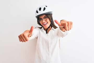 Beautiful businesswoman wearing glasses and bike helmet over isolated white background approving doing positive gesture with hand, thumbs up smiling and happy for success. Winner gesture.