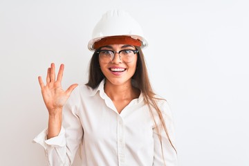 Young beautiful architect woman wearing helmet and glasses over isolated white background showing and pointing up with fingers number five while smiling confident and happy.