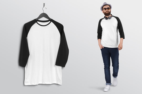 Hanging white and black plain raglan t shirt on wall along with male model in blue denim jeans pant. Isolated background