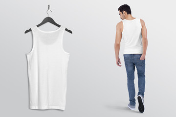 Hanging white plain tank top shirt on wall along with male model in blue denim jeans pant. Rear...