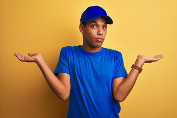 Young handsome arab delivery man standing over isolated yellow background clueless and confused...