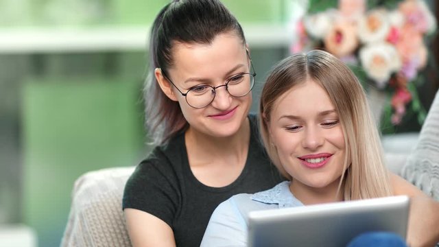 Closeup face two happy girl lesbian smiling talking enjoying entertainment movie online using tablet