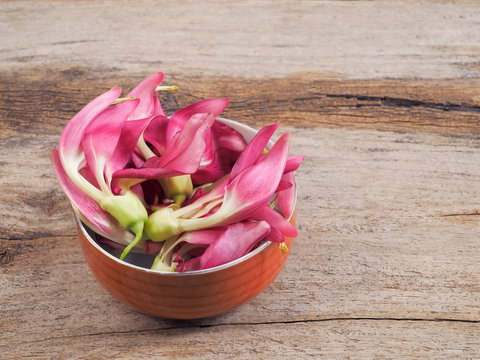 view of many Sesbania Grandiflora or Agati Grandiflora red flowers known as vegetable hummingbird, agati or hummingbird flower in orange bowl on wood texture background.