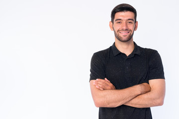Fototapeta premium Portrait of happy young bearded Persian man smiling with arms crossed