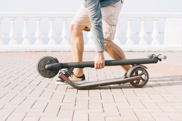 Unrecognizable man holding folding electric scooter.