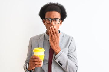 Fototapeta premium African american businessman drinking cup of coffee over isolated white background cover mouth with hand shocked with shame for mistake, expression of fear, scared in silence, secret concept