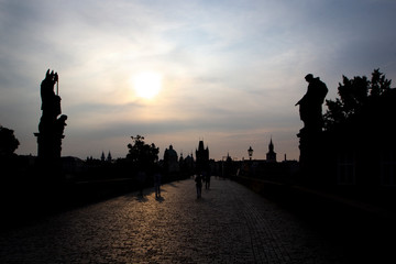 Obraz premium Silhouettes Charles Bridge, Old Town Tower, statues and happy tourists at sunrise, Prague, Czech Republic