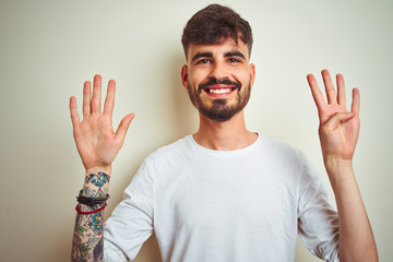 Young man with tattoo wearing t-shirt standing over isolated white background showing and pointing...