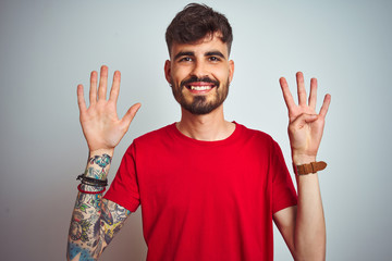 Young man with tattoo wearing red t-shirt standing over isolated white background showing and...