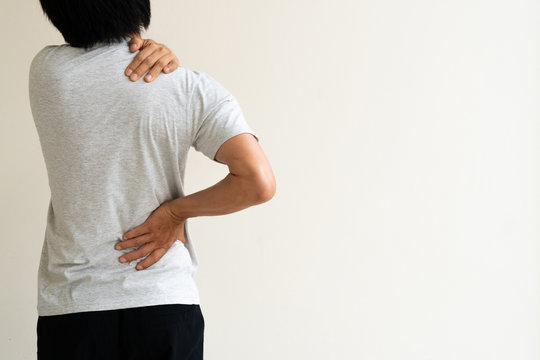 Young man holding his back in pain. Medical concept