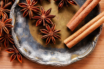 Anise seeds and cinnamon sticks on vintage plate.