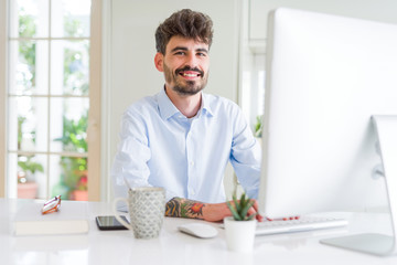 Handsome business young man working using computer, smiling confident and concentrated at the office