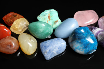 Pile of different beautiful gemstones on black background