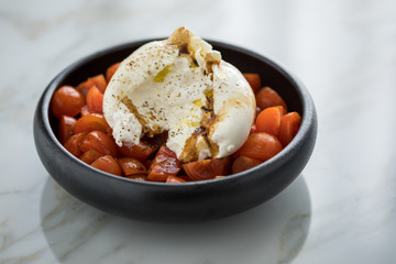 Burrata Büffelmozzarella Kugel mit Tomaten, Olivenöl und Balsamico auf schwarzen Teller