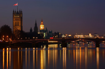 Night view of Westminster Palace over illuminated Thames River.