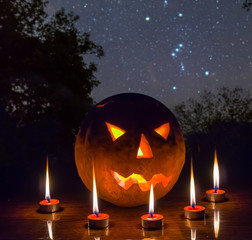 halloween night scene, jack o lantern pumpkin arond candle on the night forest glade under starry sky