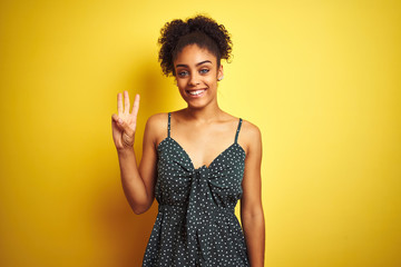African american woman wearing summer casual green dress over isolated yellow background showing and pointing up with fingers number three while smiling confident and happy.