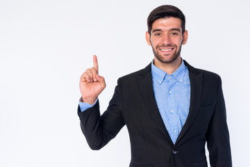 Portrait of happy young bearded Persian businessman pointing up