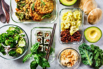 Healthy vegan food in glass containers. Flat lay of stew with chickpeas, vegan bergrer, hummus,...