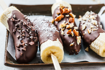 Vegan dessert for kids. Banana in dark chocolate with nuts.