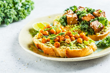 Vegan open sandwiches with guacamole, tofu, chickpeas and sprouts on a plate.