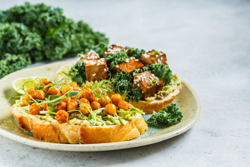 Vegan open sandwiches with guacamole, tofu, chickpeas and sprouts on a plate.