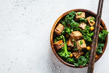Poster Teriyaki tofu salad with kale and chickpeas in a wooden bowl, copy space, top view. © vaaseenaa