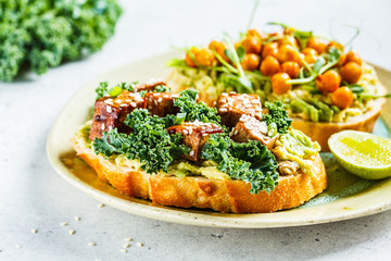 Vegan open sandwiches with guacamole, tofu, chickpeas and sprouts on a plate.