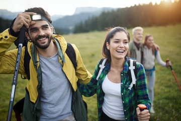 Group of hikers with backpacks and sticks walking on mountain. Friends making an excursion