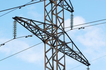High-voltage technological power lines on metal poles with powerful power wires against the sky