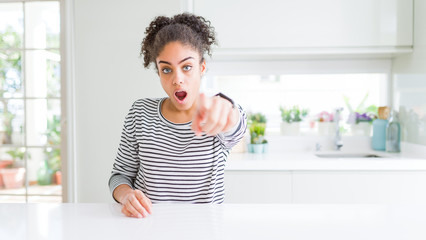 Beautiful african american woman with afro hair wearing casual striped sweater pointing displeased and frustrated to the camera, angry and furious with you