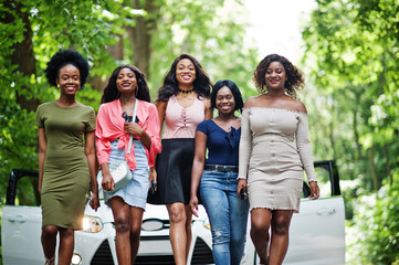 Group of five happy african american walking against white car.