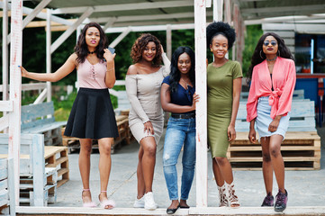 Obraz premium Group of five african american girls relaxing at beach outside cafe.