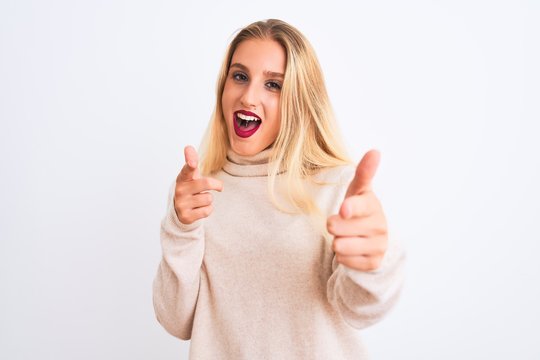 Young beautiful woman wearing turtleneck sweater standing over isolated white background pointing fingers to camera with happy and funny face. Good energy and vibes.