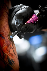Fototapeta na wymiar Female tattoo artist making tattoo on a men’s arm