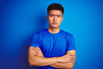 Young asian chinese man wearing t-shirt standing over isolated blue background skeptic and nervous,...