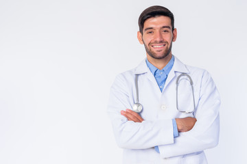 Portrait of happy young bearded Persian man doctor smiling with arms crossed