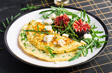 Omelette with feta cheese, parsley and salad with figs, arugula on white plate. Frittata - italian omelet.