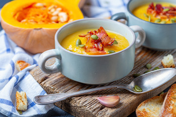 Pumpkin soup with crispy bacon close up.