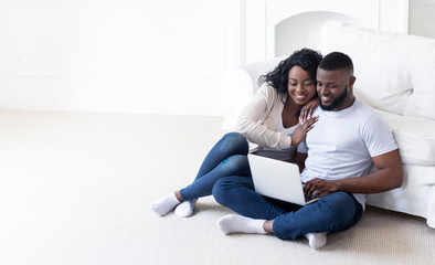 African american couple sitting on floor with laptop