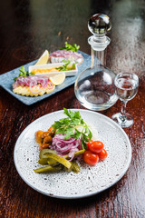 Traditional Russian appetizer and vodka, sauerkraut with cranberries, herring, pickled cucumbers, pickled mushrooms and tomatoes.